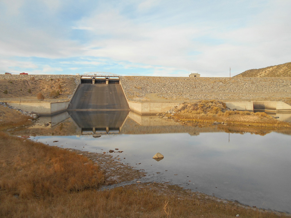 View of Bull Lake Dam with released water in foreground.