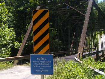 Warning sign at entrance of historic bridge.