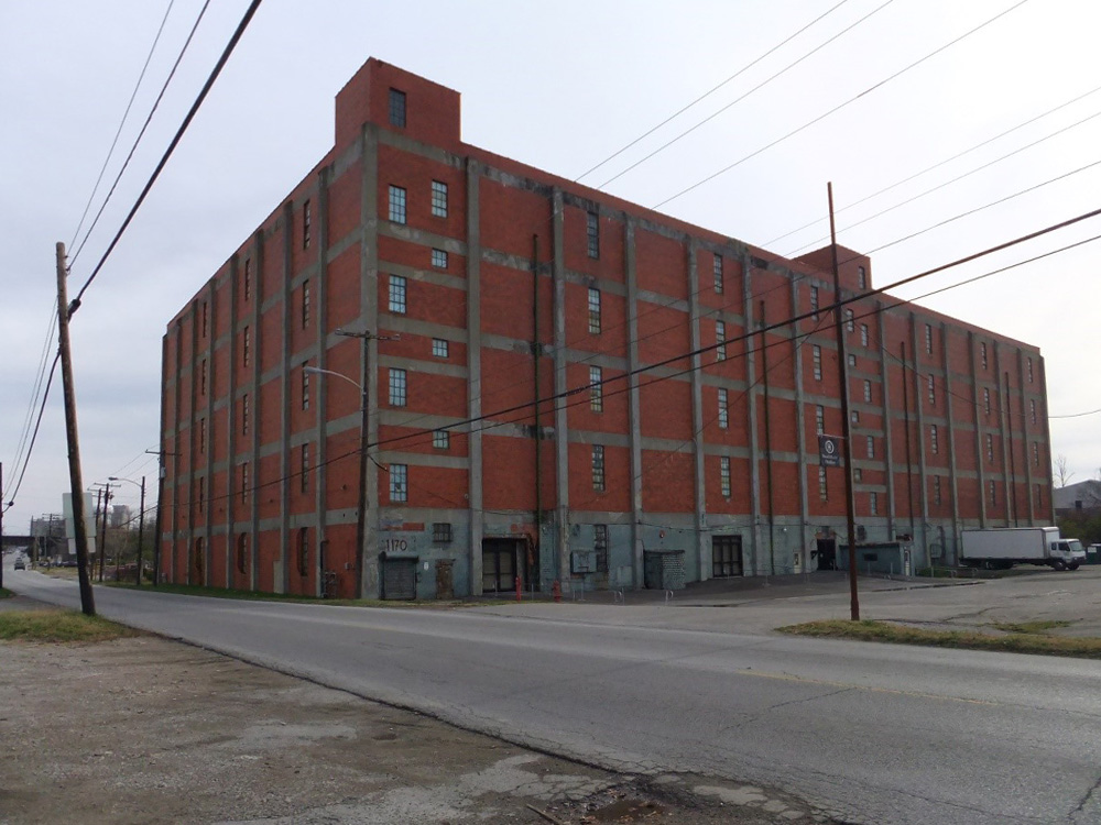 Large, multi-story, brick distillery building.