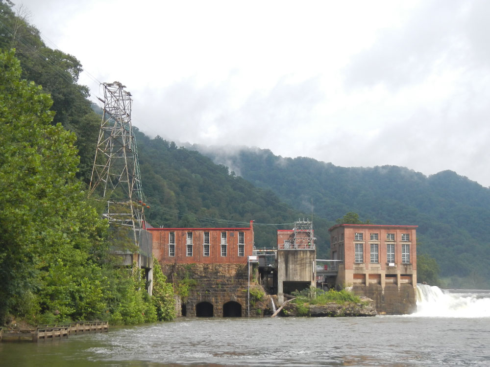 Historic multi-story buildings associated with hydroelectric power operations, viewed from across river.
