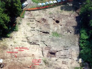 Aerial view of excavated area of former homestead, showing evidence of root cellars, house foundations, a privy, and other features.