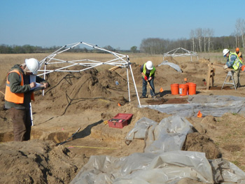 Crewmembers conducting fieldwork in open, excavated field.