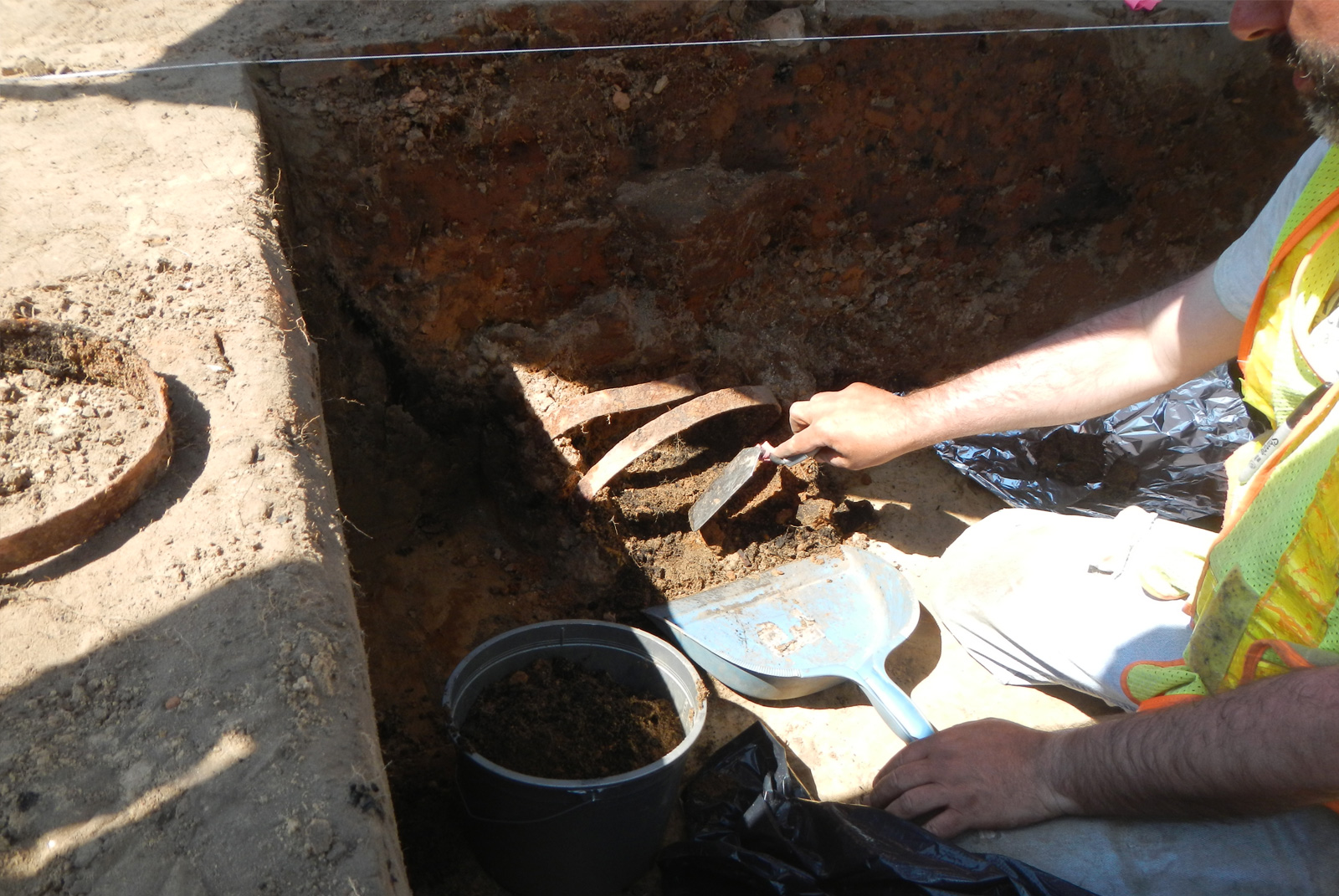 Crewmember uncovering rusted metal pieces while performing excavation.