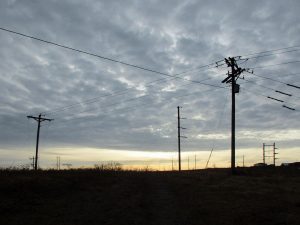 Powerlines silhouetted against cloudy sky.