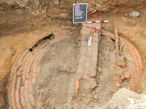 Overview of excavated foundation overtop of a cistern constructed of bricks.