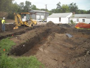 Bulldozer digging deep trenches in project area.