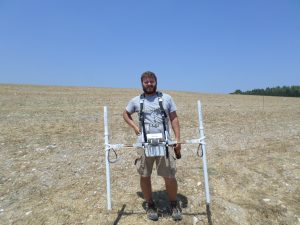 Dr. Menzer standing in open field, harnessed with GPR equipment.