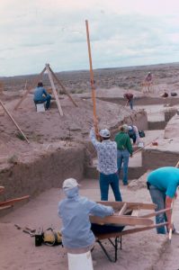 Crewmembers conducting fieldwork in large, open, excavated area.