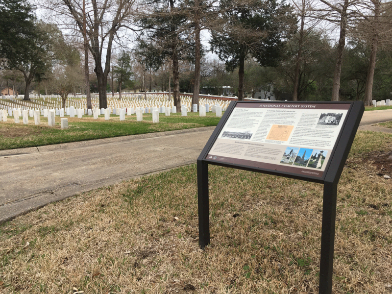 Infographic sign about the National Cemetery System pictured with military cemetery in background.