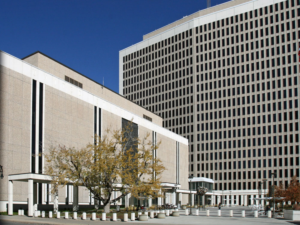Overview of courthouse with much larger concrete building adjacent in background.