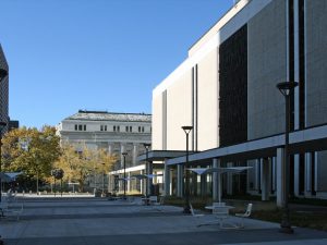 Overview of courtyard area outside large concrete courthouse building.