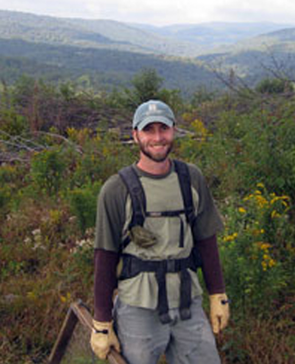 Jason pictured with vast, wooded mountain terrain in background.