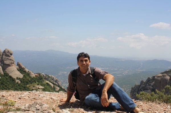 Jay seated in front of vast overlook with mountains in distance.