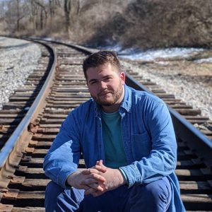 Evan sitting on railroad tracks.